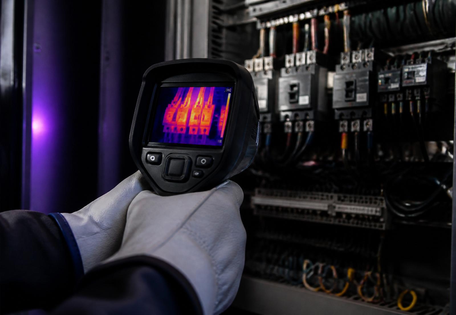 Technician performing thermographic inspection on an electrical panel